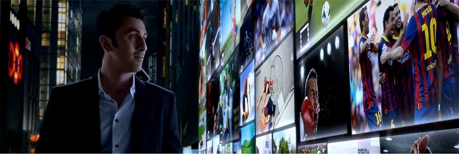 Man walking past a wall of TV screens showing sports highlights