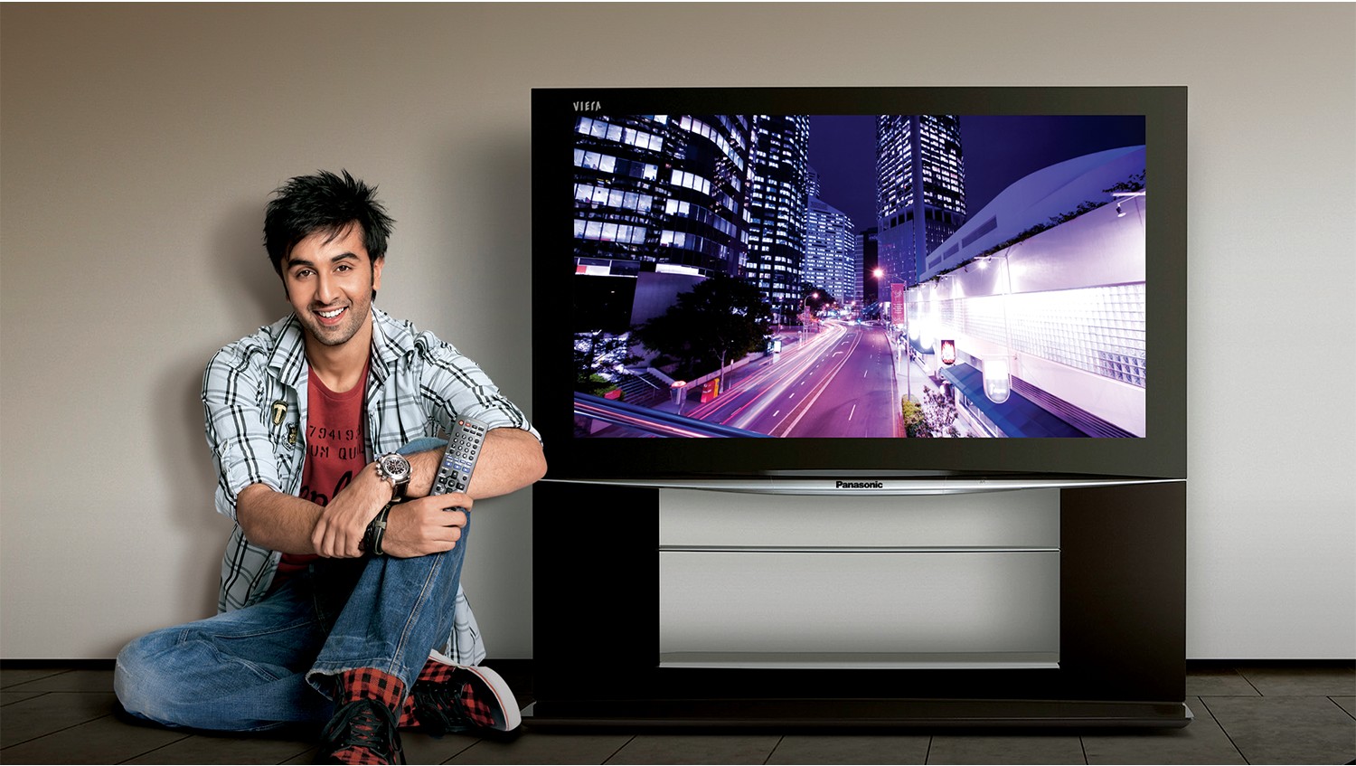 Man sitting beside a Panasonic Viera TV showing a city skyline