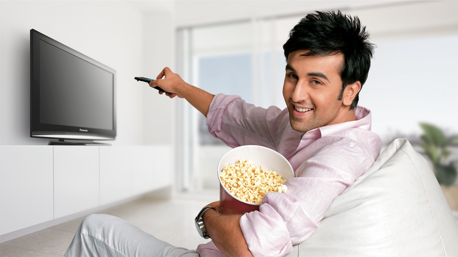 Ranbir Kapoor on a beanbag with popcorn, pointing a remote at a Panasonic Viera TV